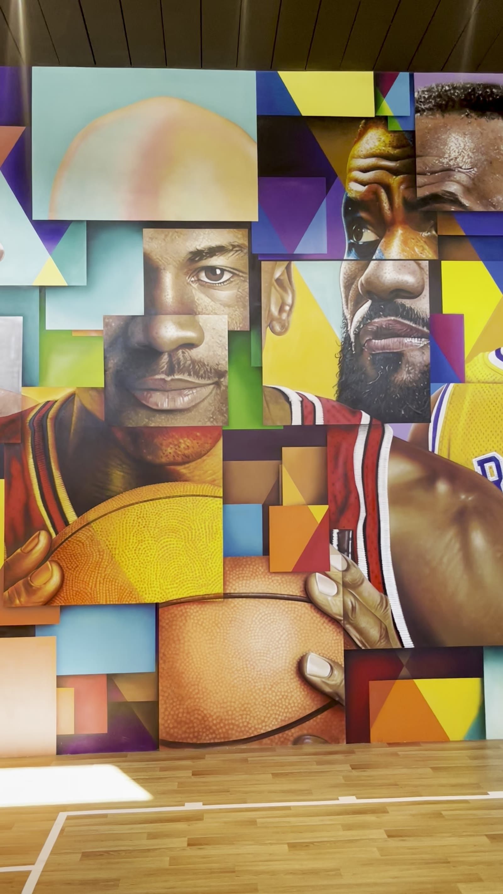 Mural em quadra de basquete com ícones do esporte em composição fragmentada.